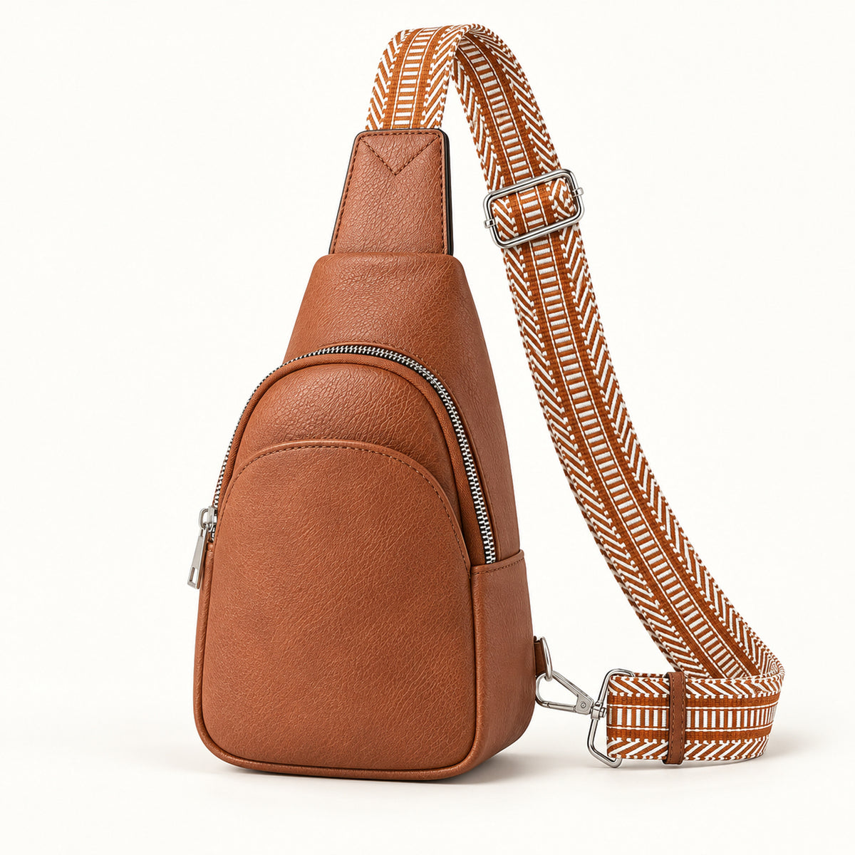 Cognac Brown teardrop sling bag with rust and ivory geometric woven strap and silver-tone hardware on an ivory background.