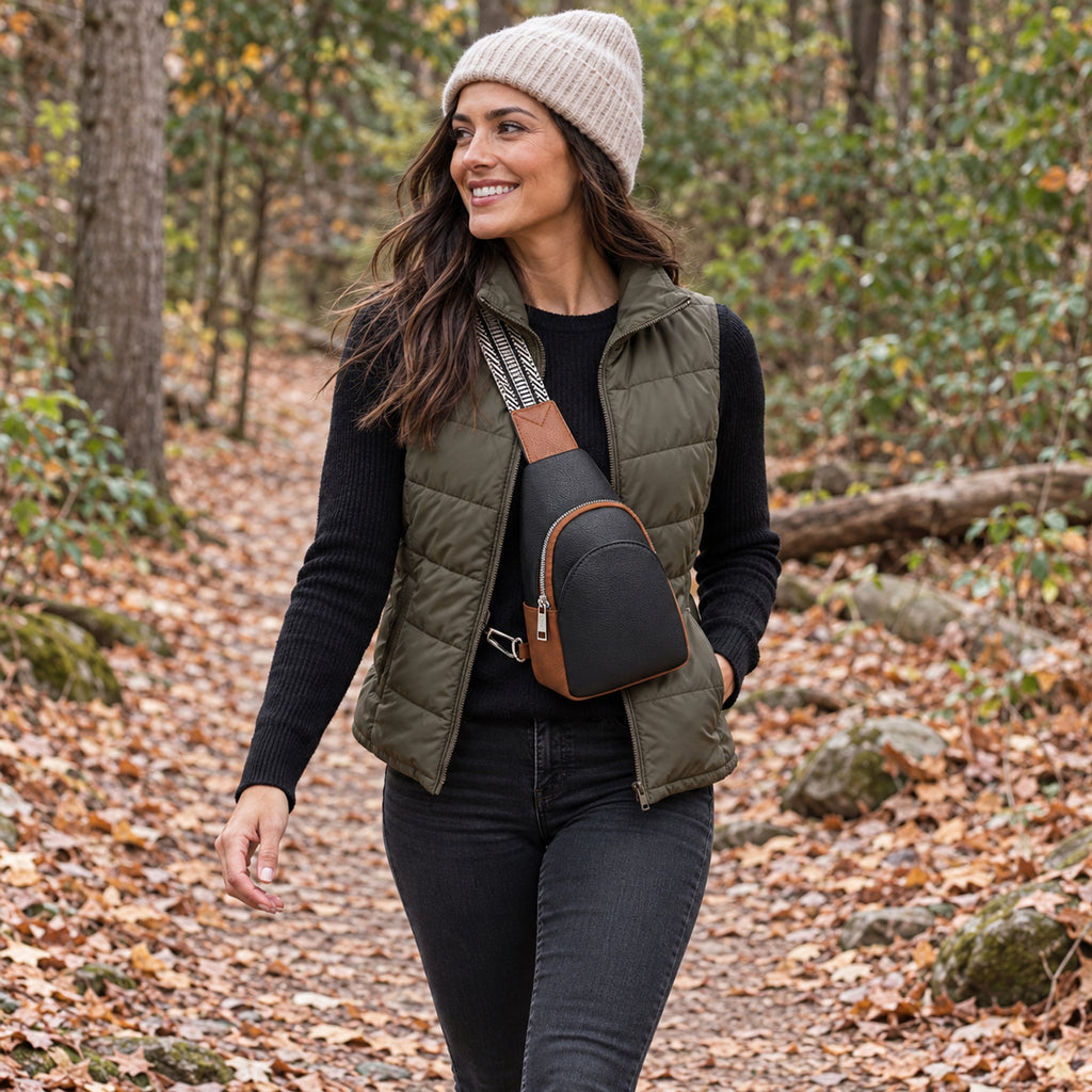 Woman walking along a woodland path wearing the Black and Cognac sling bag with its black and ivory woven strap.