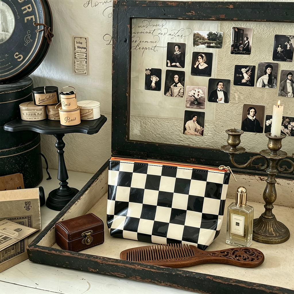 Black and Cream checkerboard makeup bag on a vintage vanity with an ornate comb, perfume bottle and antique-style decor. Styling props are not included.